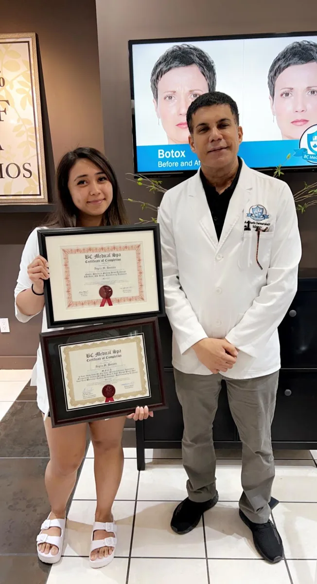 BC Medical graduate holding their framed certificate with their instructor at the Coquitlam campus