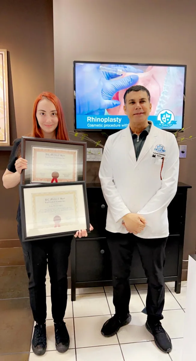 BC Medical graduate holding their framed certificate with their instructor at the Coquitlam campus